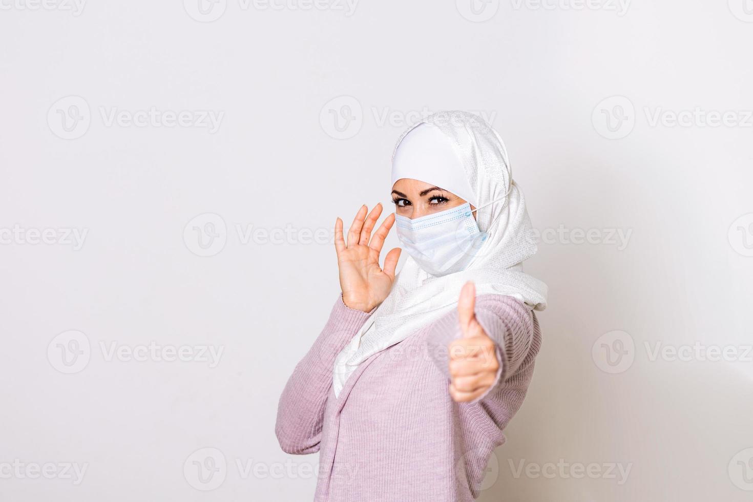 moslim vrouw met beschermend masker tonen duim omhoog. vrouw met gezicht masker in hijaab, bescherming van coronavirus in menselijk longen. mers-cov, sar, adenovirussen en andere ademhalings virussen foto