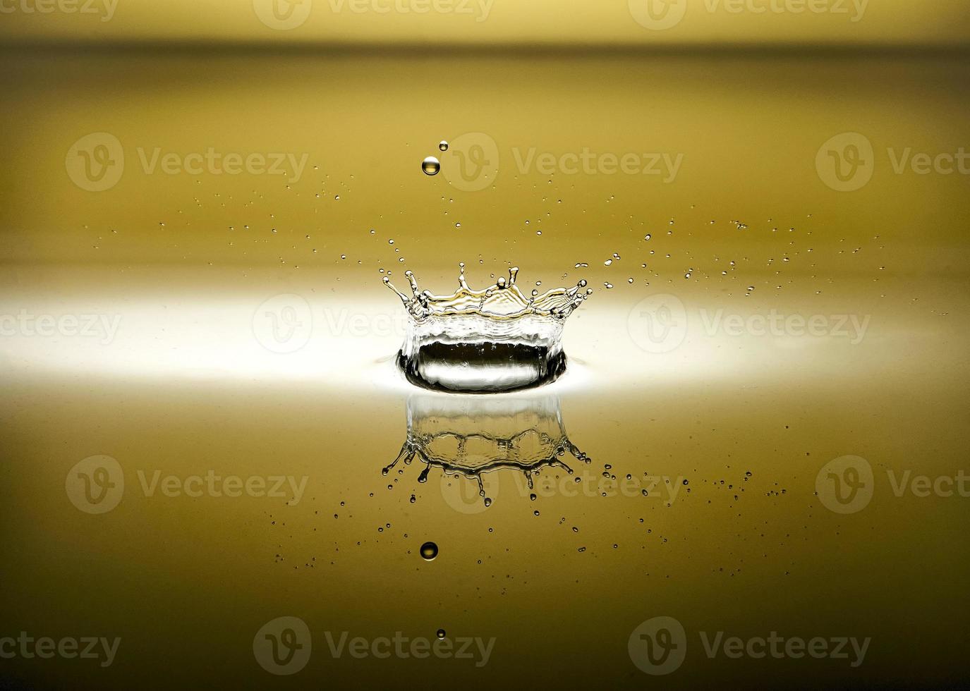 plons van water met reflectie en druppels Aan een geel achtergrond foto
