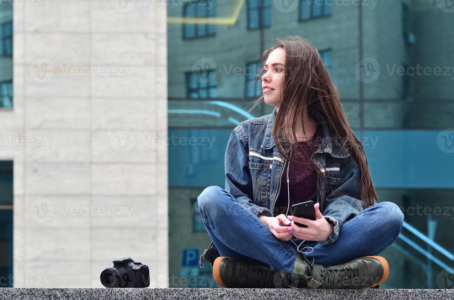 een meisje fotograaf toepassingen een smartphone en zit Aan een graniet para foto