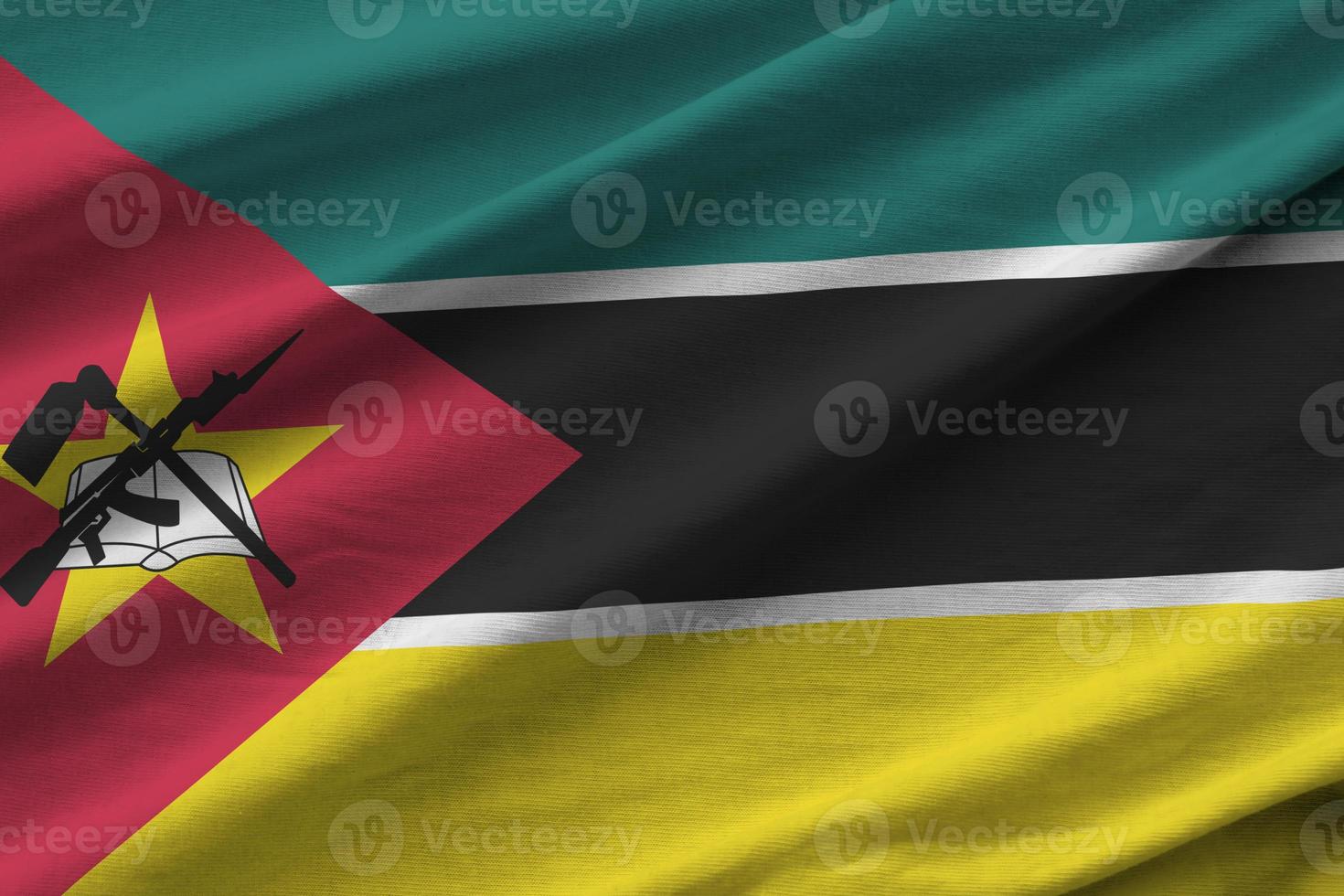 Mozambique vlag met groot vouwen golvend dichtbij omhoog onder de studio licht binnenshuis. de officieel symbolen en kleuren in banier foto