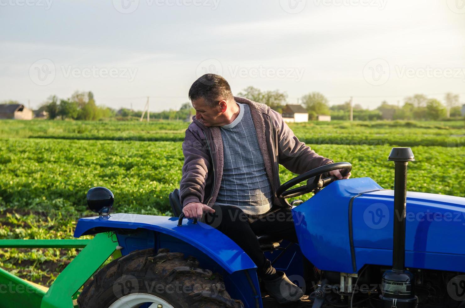 een boer Aan een trekker monitoren de operatie van uitrusting voor oogsten aardappelen. landbouw en landbouwgrond. makkelijker maken snelheid omhoog werk met technologie en machines. agro industrie en agribusiness foto