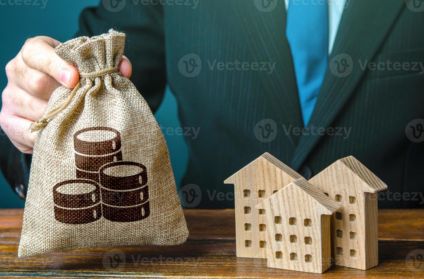 geld zak in een hand- en woon- gebouwen figuren. investeringen in echt landgoed en bouw industrie. bank aanbod van hypotheek lening. verhuur bedrijf. uitverkoop van huisvesting. kopen. gemeentelijk begroting. belastingen foto