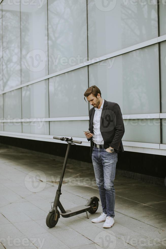 jonge zakenman met behulp van mobiele telefoon op elektrische scooter foto