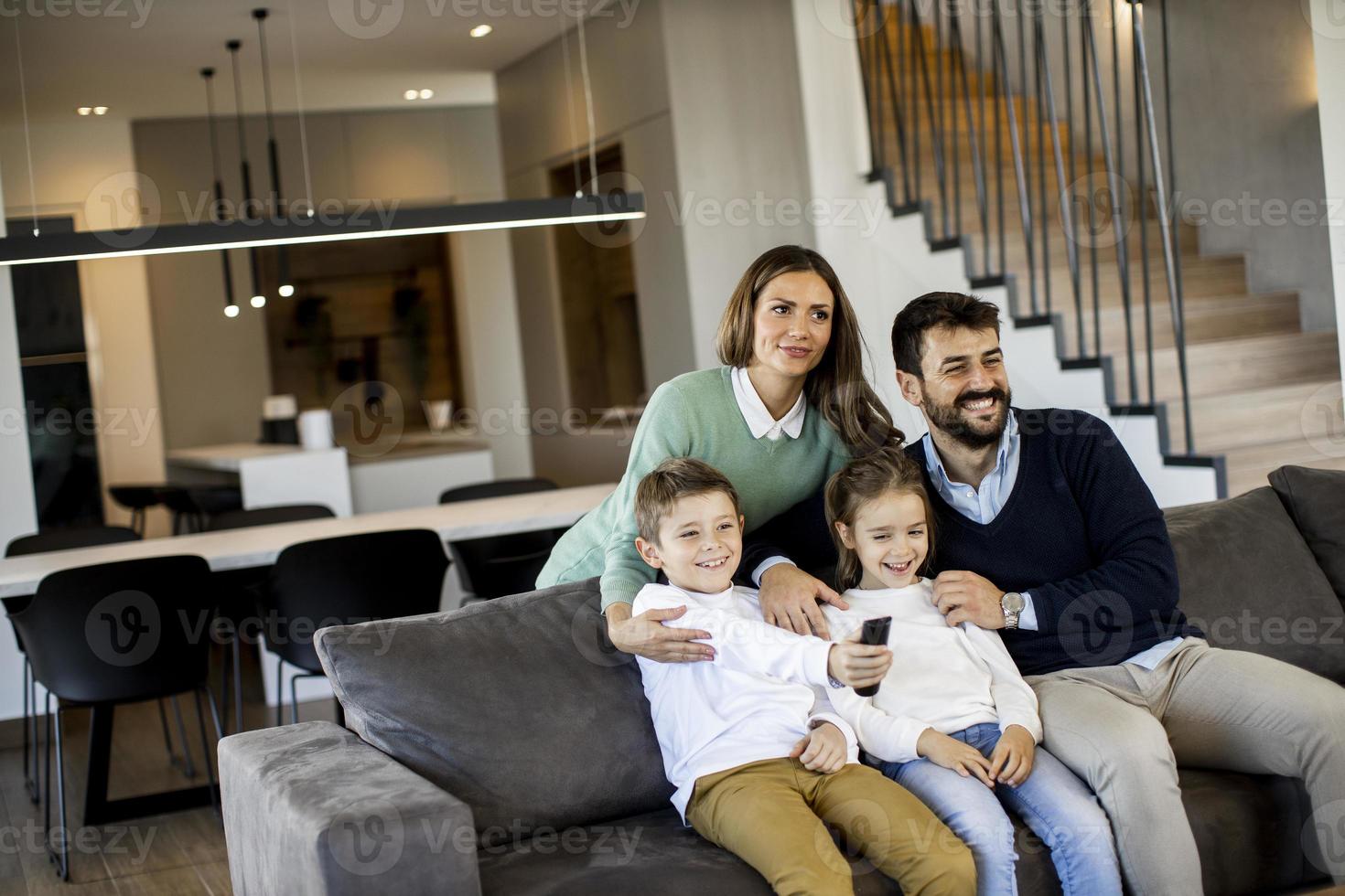 jong familie aan het kijken TV samen Aan de sofa in de leven kamer foto