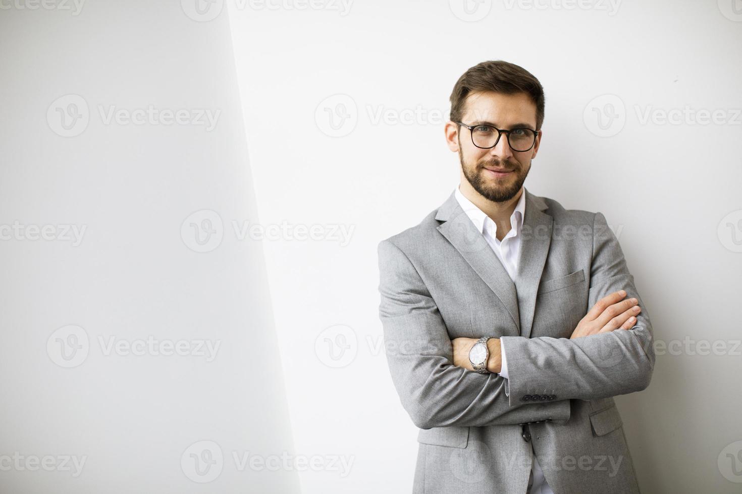 jong modern zakenman staand door de muur in de kantoor foto