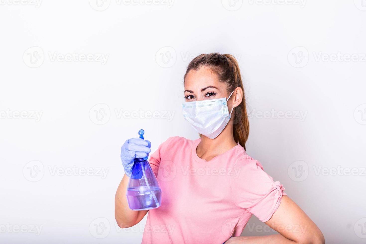 vrouw met beschermend gelaats masker en ontsmettingsmiddel verstuiven fles . ze sprenkeling ontsmettingsmiddel en schoonmaak de glas. blijven veilig. foto