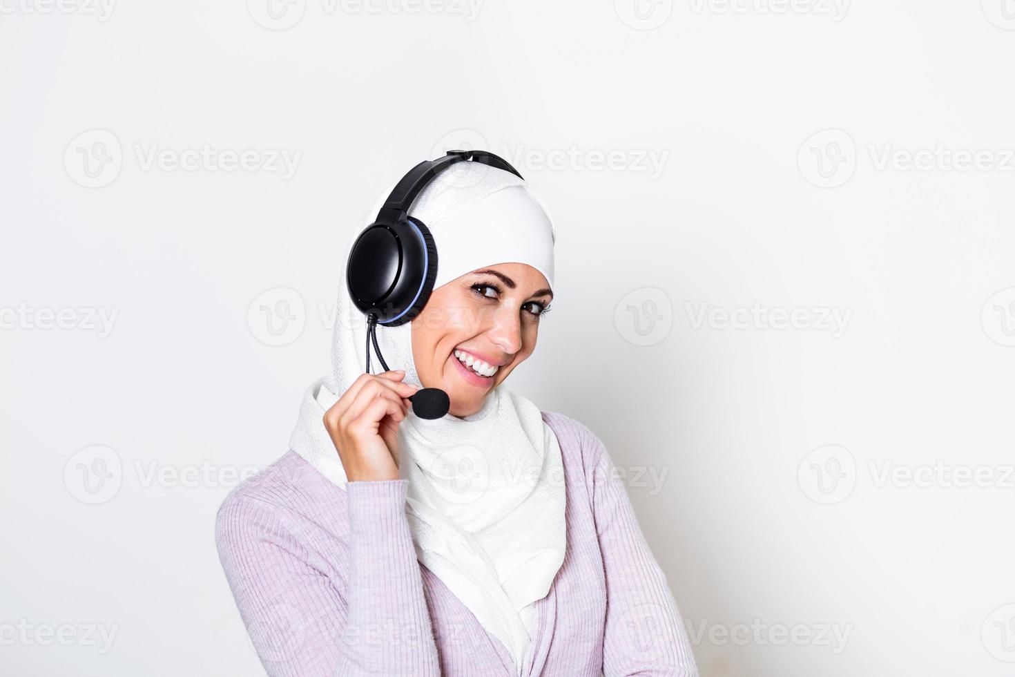 jong moslim vrouw met hijab sjaal klant vertegenwoordiger bedrijf vrouw met telefoon koptelefoon helpen en ondersteunen online met klant in modern telefoontje centrum foto