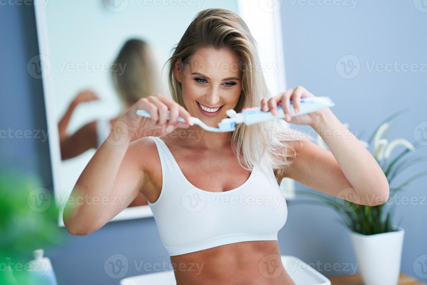 mooi vrouw poetsen tanden in de badkamer foto