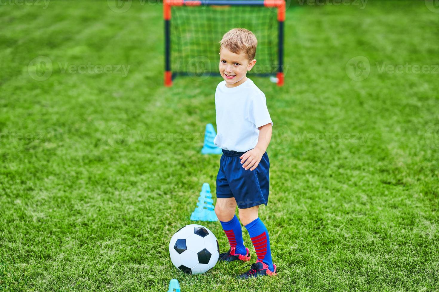 weinig jongen beoefenen voetbal buitenshuis foto