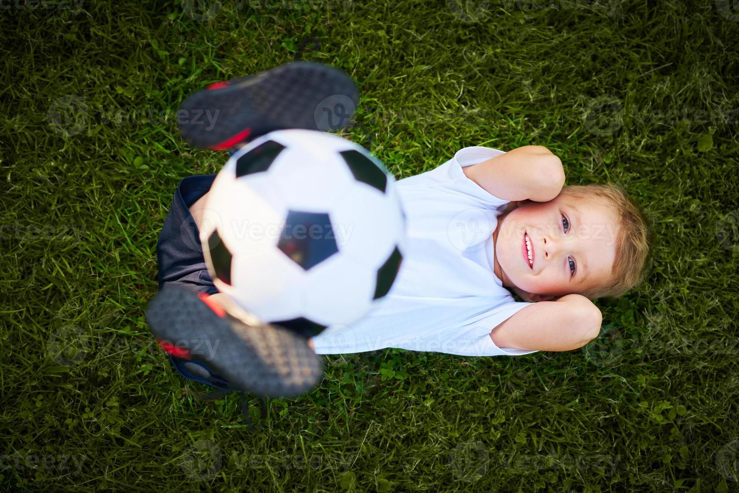 weinig jongen beoefenen voetbal buitenshuis foto