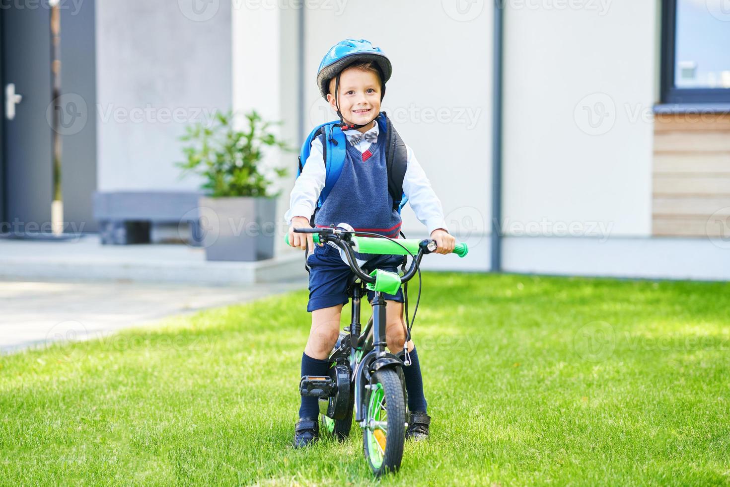 school- jongen in veiligheid helm rijden fiets met rugzak foto