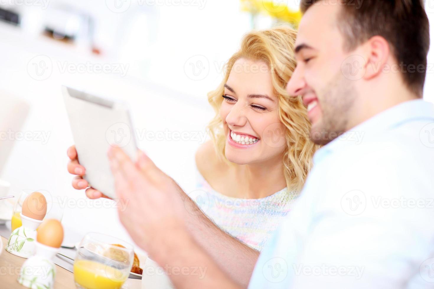 gelukkig paar aan het eten ontbijt en gebruik makend van tablet foto