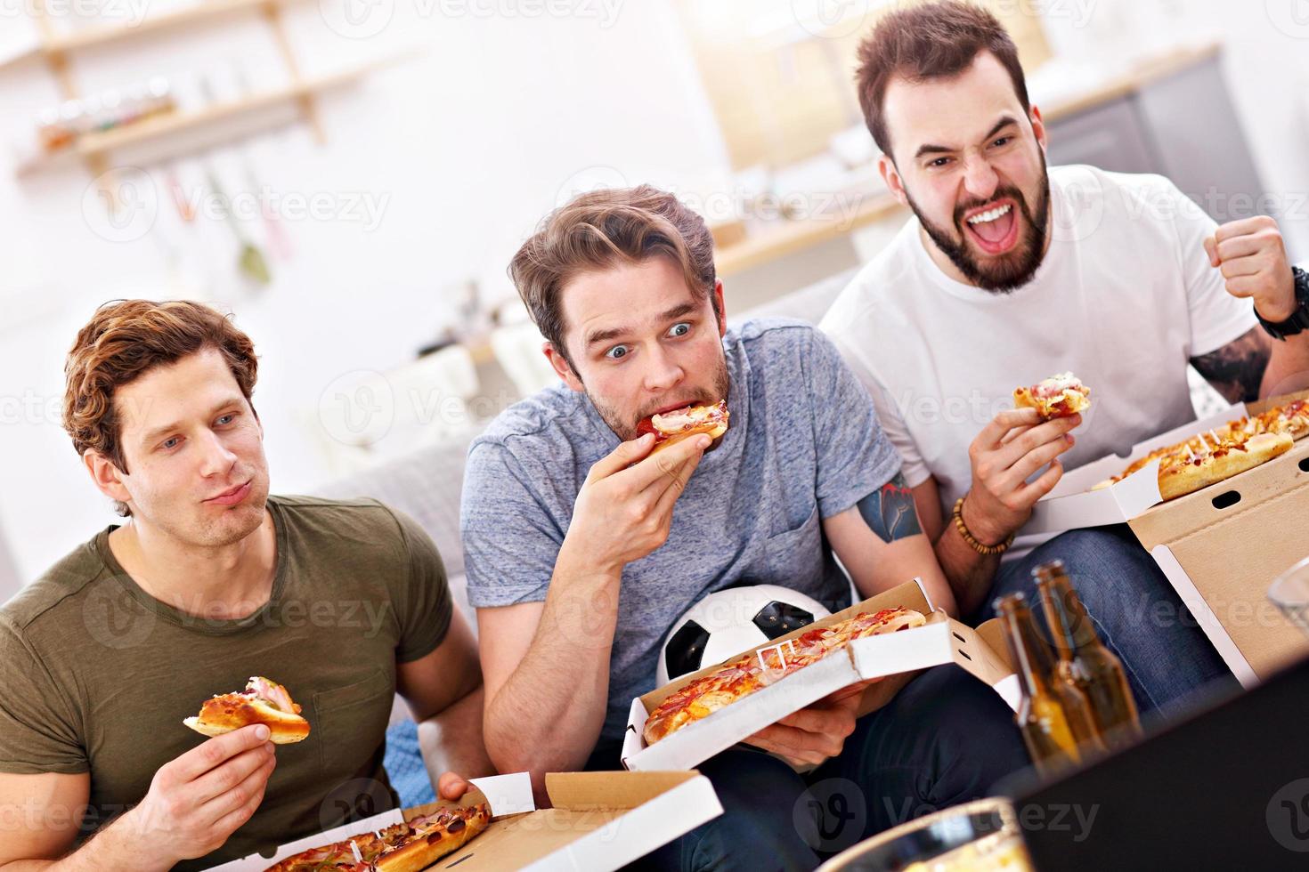 gelukkig mannetje vrienden aan het eten pizza en aan het kijken TV foto