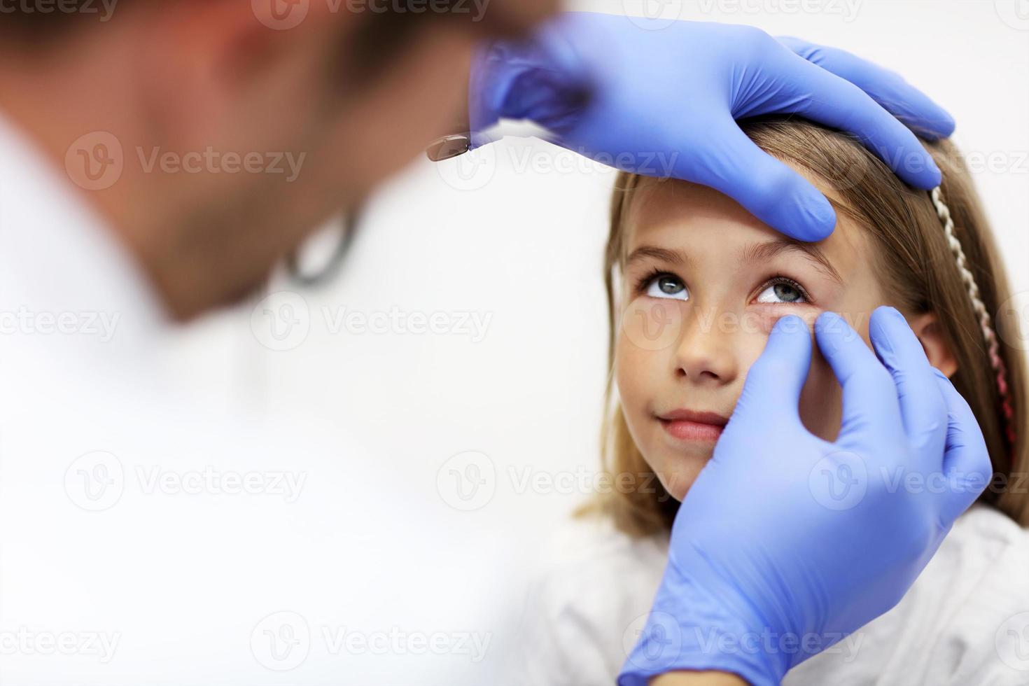 kind mannetje optometrist onderzoekt gezichtsvermogen van weinig meisje foto