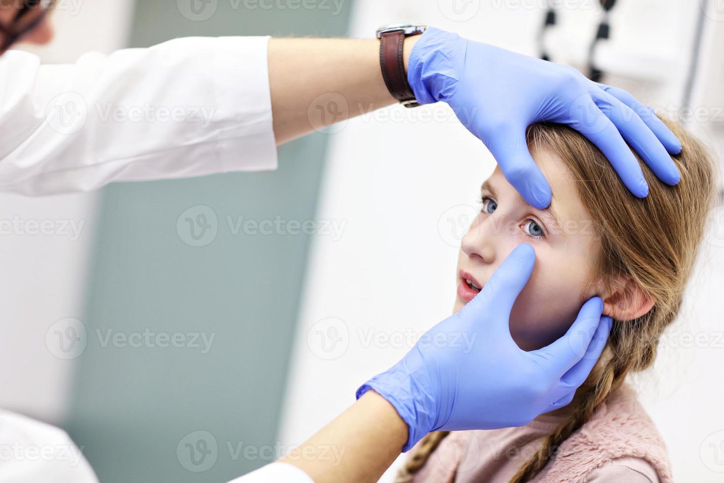 kind mannetje optometrist onderzoekt gezichtsvermogen van weinig meisje foto