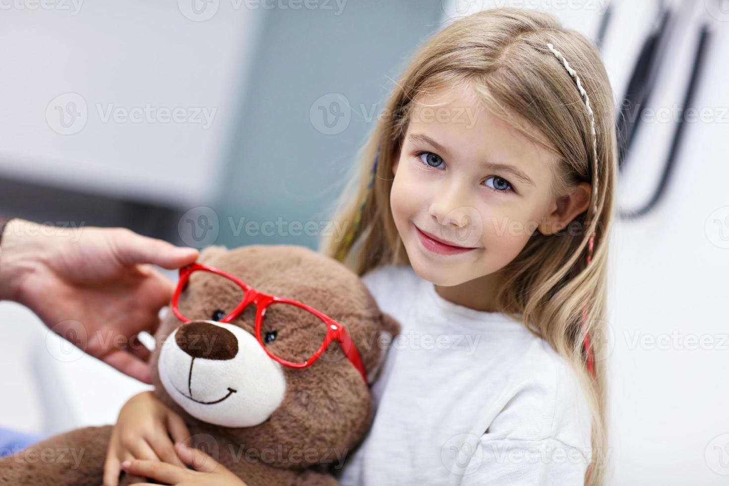 kind mannetje optometrist onderzoekt gezichtsvermogen van weinig meisje foto