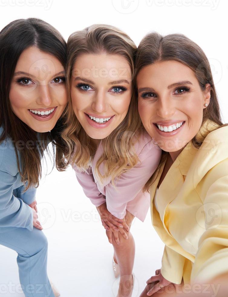 drie Dames in pastel pakken poseren over- wit achtergrond foto