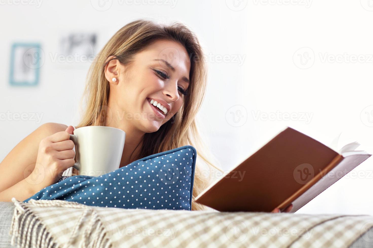 gelukkig vrouw lezing Aan sofa foto