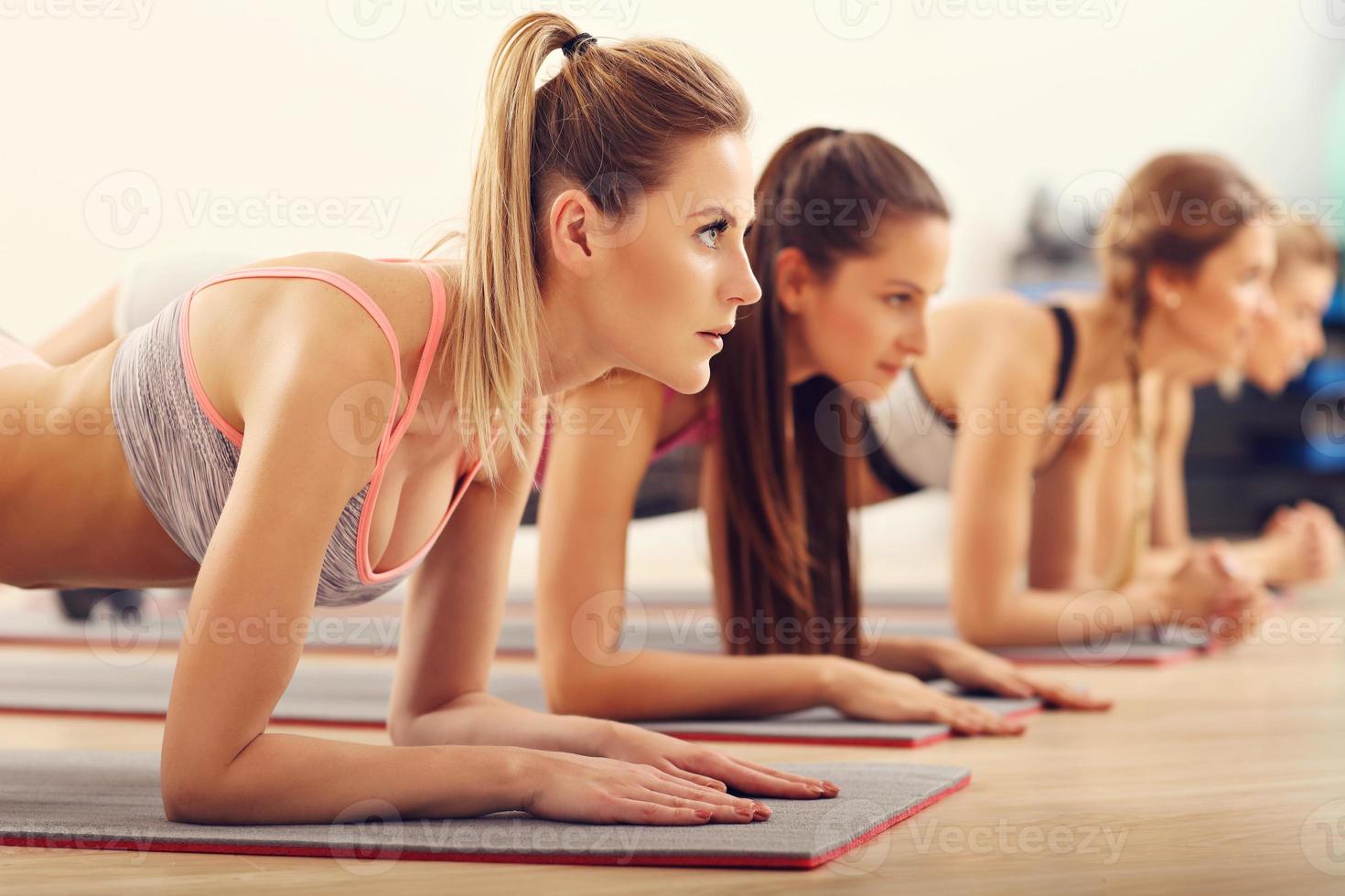 groep van jong Dames aan het doen plank samen in Sportschool foto