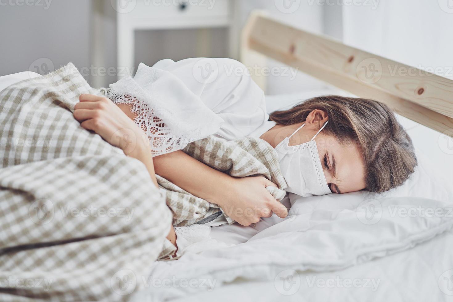 volwassen vrouw in masker gevoel ziek Bij huis covid-19 concept foto