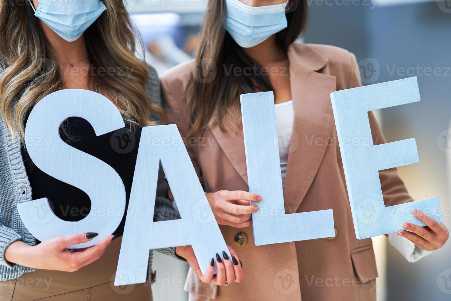 twee meisjes Aan boodschappen doen Holding uitverkoop percentage teken in masker foto