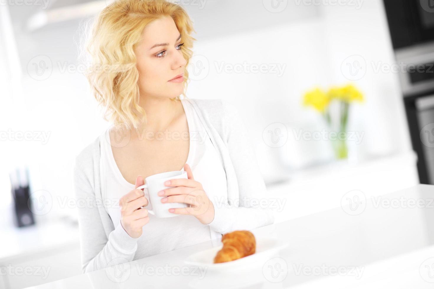 jong vrouw drinken koffie in de keuken foto