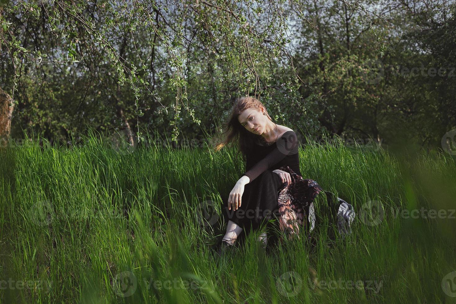 vrouw staren direct en zittend in hoog gras toneel- fotografie foto