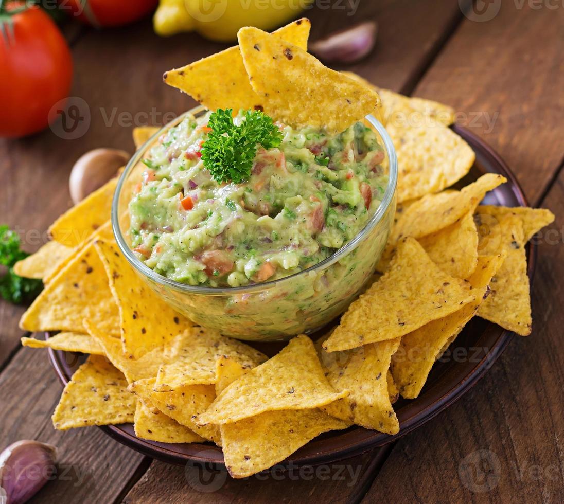 guacamole avocado, limoen, tomaat, ui en koriander, geserveerd met nacho's - traditionele Mexicaanse snack foto