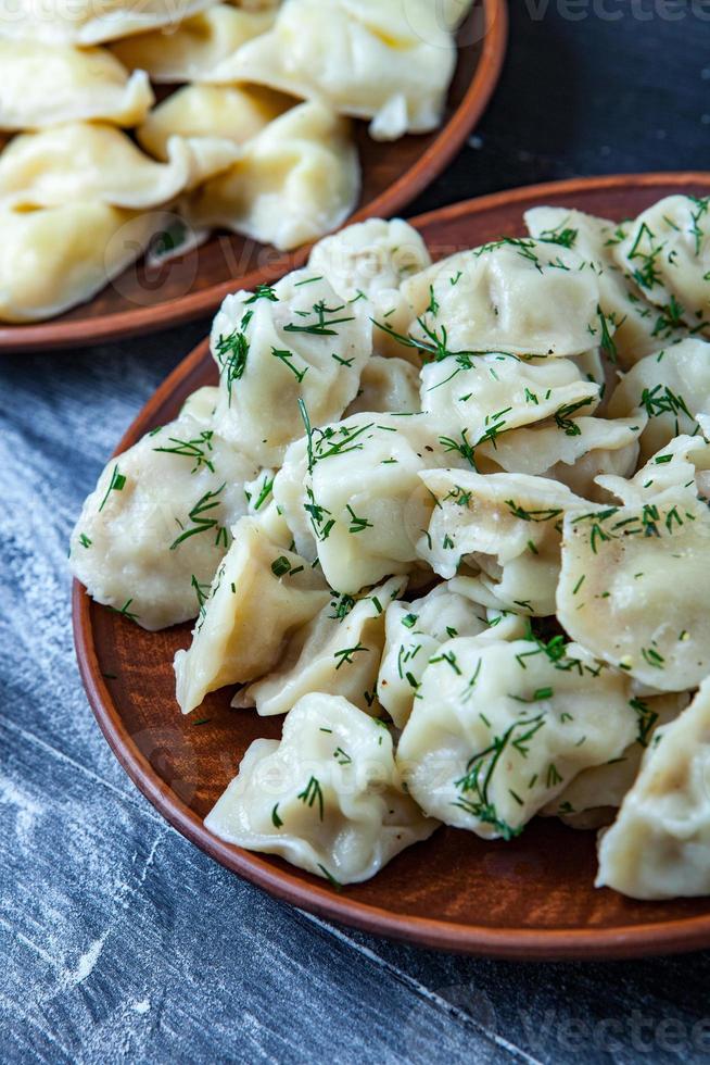 traditioneel Russisch pelmeni of ravioli, knoedels met vlees Aan hout zwart achtergrond. Russisch voedsel en Russisch keuken concept. foto