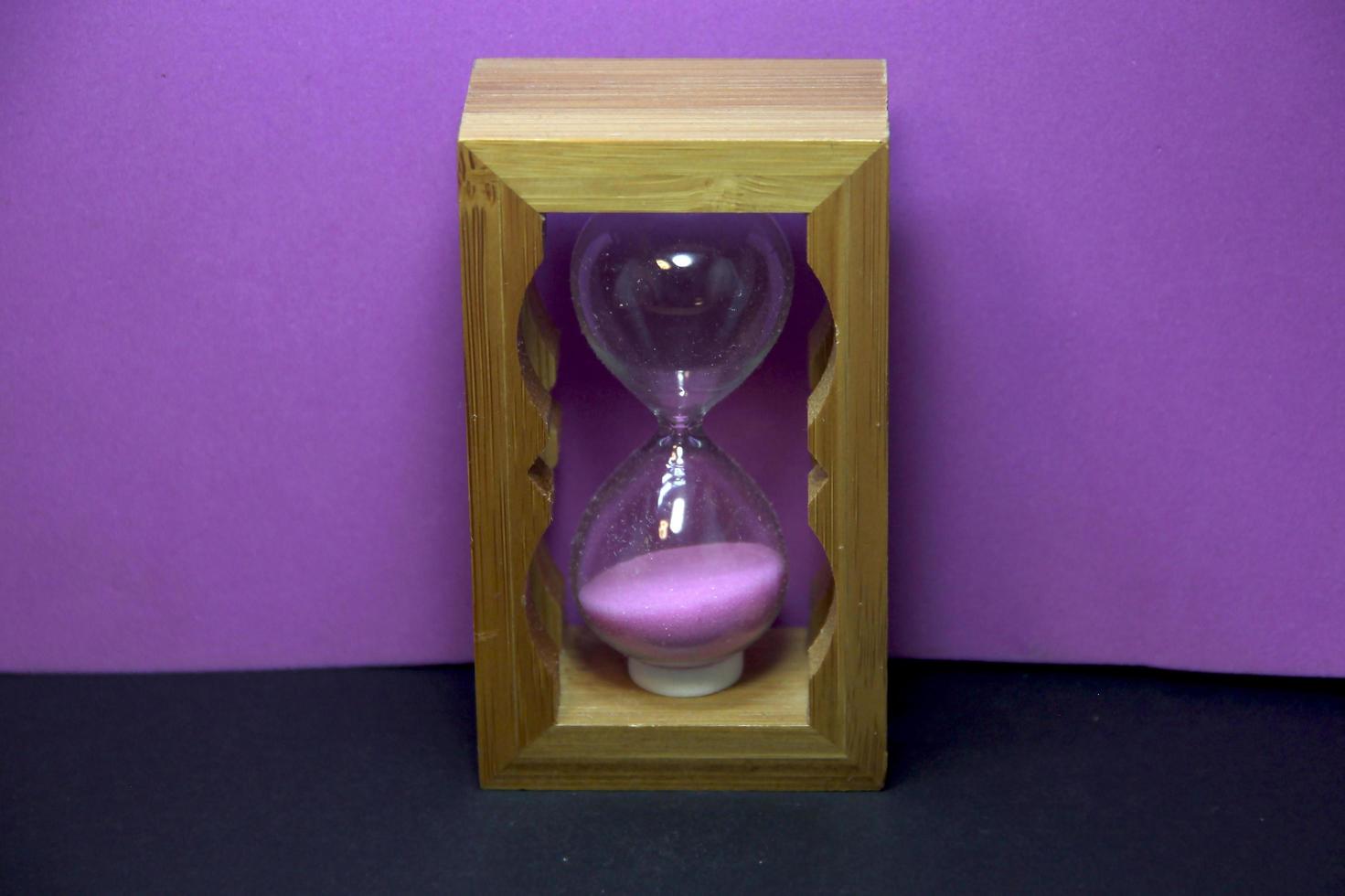 houten roze zand zandloper. klein zand glas foto decoratie geïsoleerd Aan Purper en zwart achtergrond. Nee tekst met ruimte voor kopiëren ruimte.