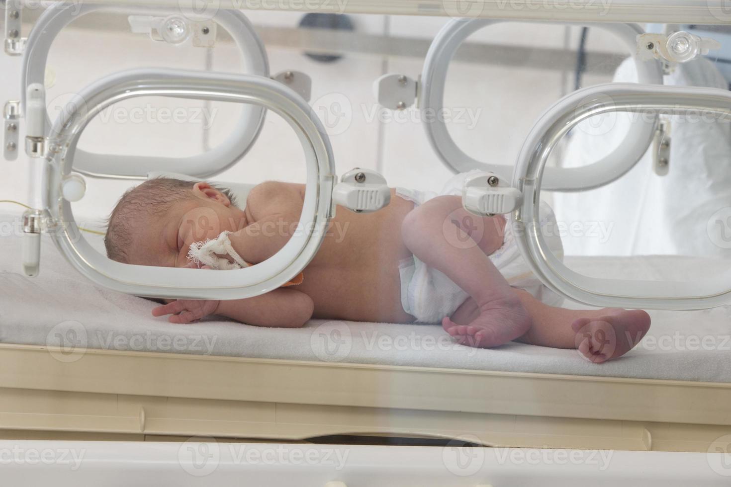 een prematuur pasgeboren in een speciaal incubator in de kinderen afdeling van de ziekenhuis. foto