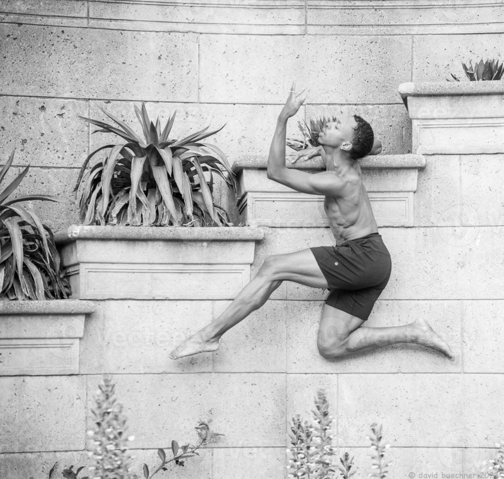 jong danser gepositioneerd tegen een planter in een atletisch houding foto