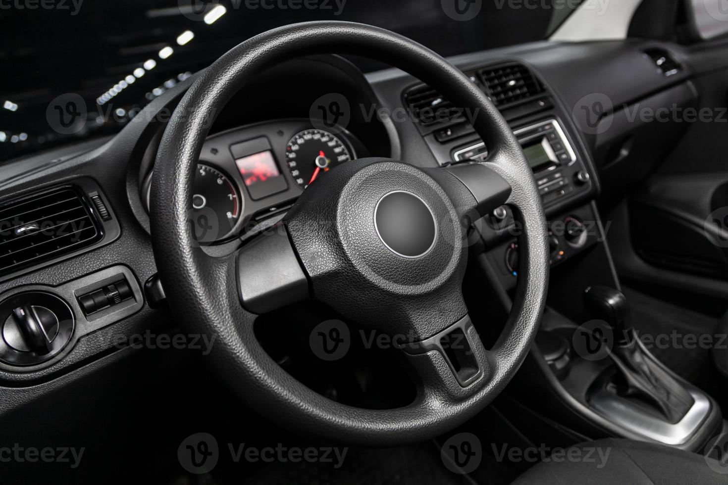 dashboard, snelheidsmeter, snelheidsmeter en stuurinrichting wiel met houten inzetstukken met telefoon instelling en volume toetsen. luxueus auto interieur details foto