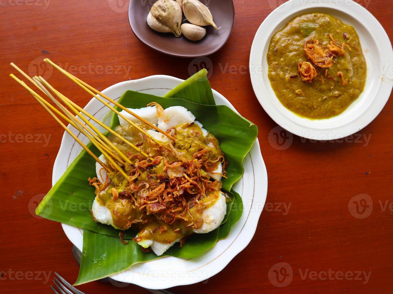 saté padang of saté padang is pittig rundvlees saté van padang, west sumatra. geserveerd met pittig kerrie saus en rijst- taart, lontong Aan banaan blad. geïsoleerd Aan wit achtergrond foto