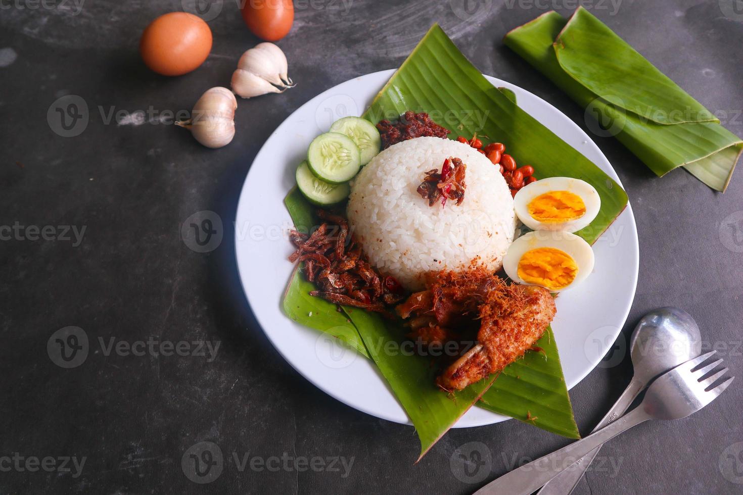 nasi lemak, is traditioneel Maleis gemaakt gekookt eieren, bonen, ansjovis, Chili saus, komkommer. van schotel geserveerd Aan een banaan blad foto