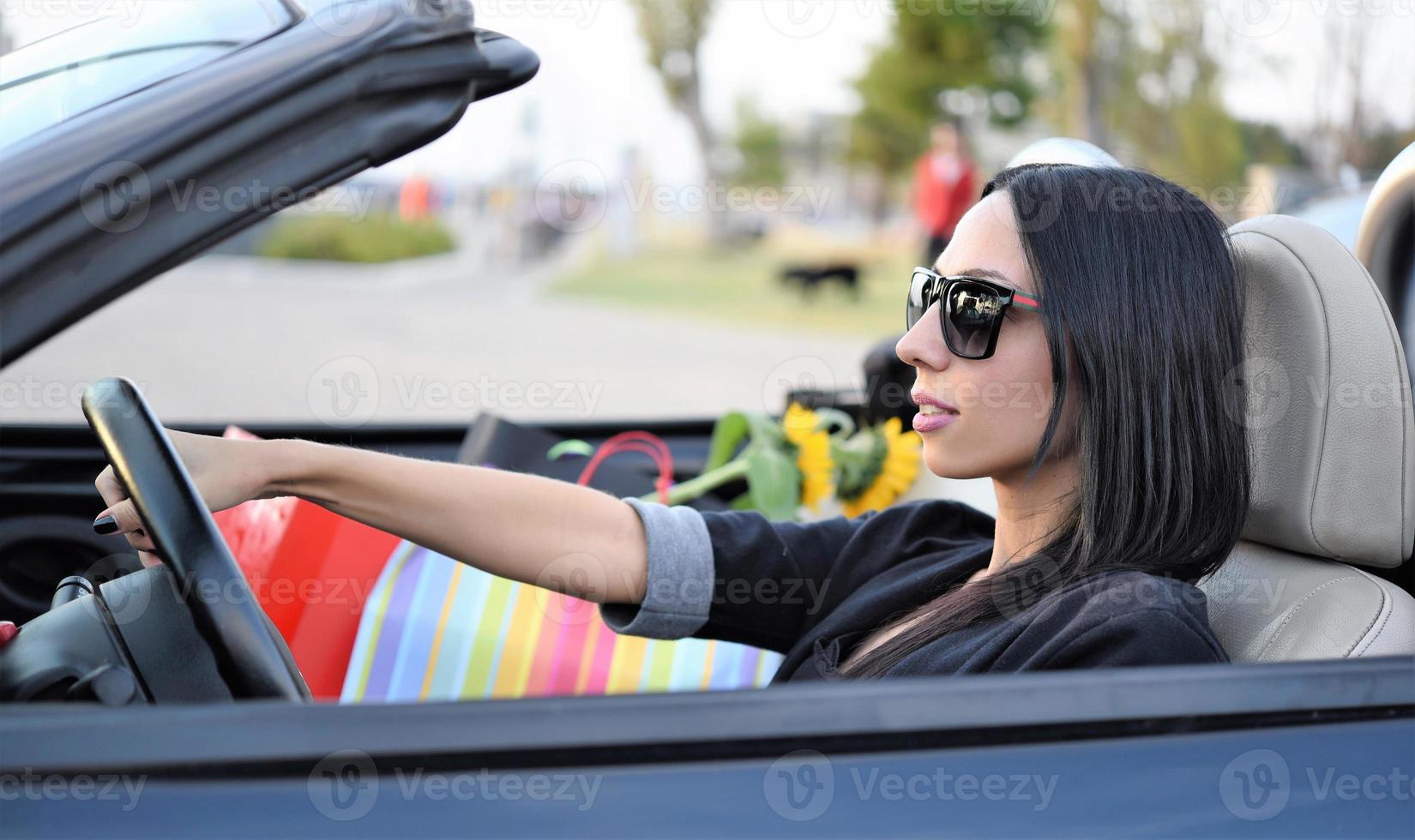 gelukkig mooi vrouw het rijden een sport- converteerbaar auto in de stad foto