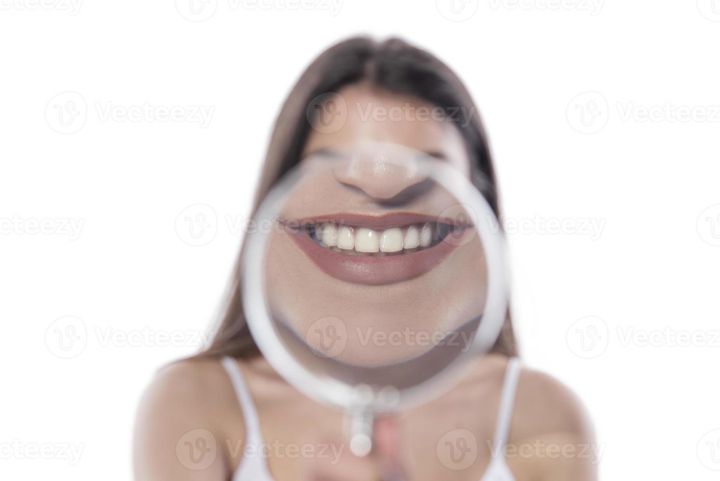 jong vrouw met perfect glimlach en gezond tanden achter vergroten glas foto