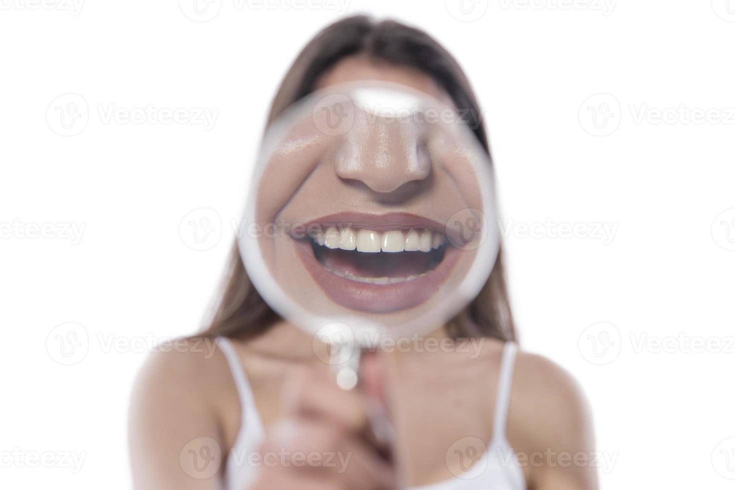 jong vrouw met perfect glimlach en gezond tanden achter vergroten glas foto