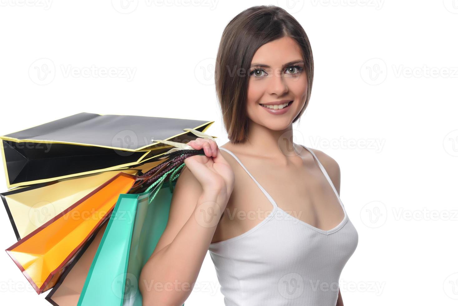 beeld van een mooi jong brunette dame poseren met boodschappen doen Tassen en op zoek Bij camera. boodschappen doen concept. geïsoleerd foto