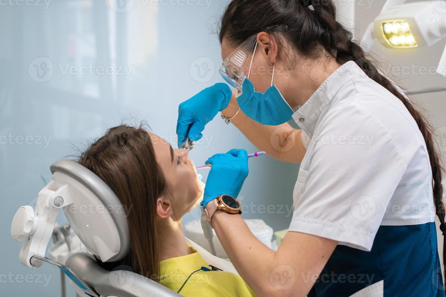 tandarts behandelt tanden naar een meisje in een kliniek foto