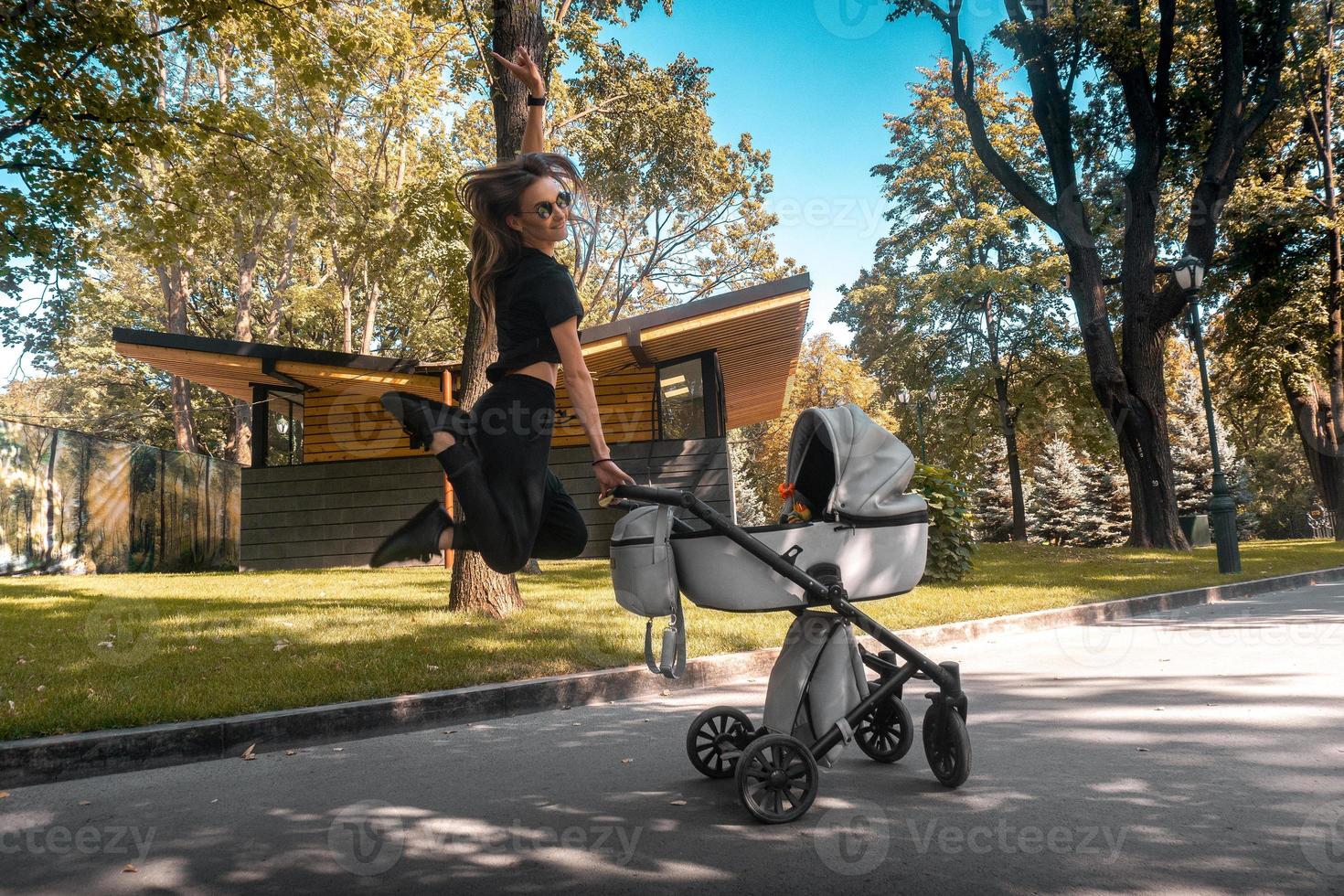 vrolijk elegant jong moeder vliegend over de wandelwagen foto