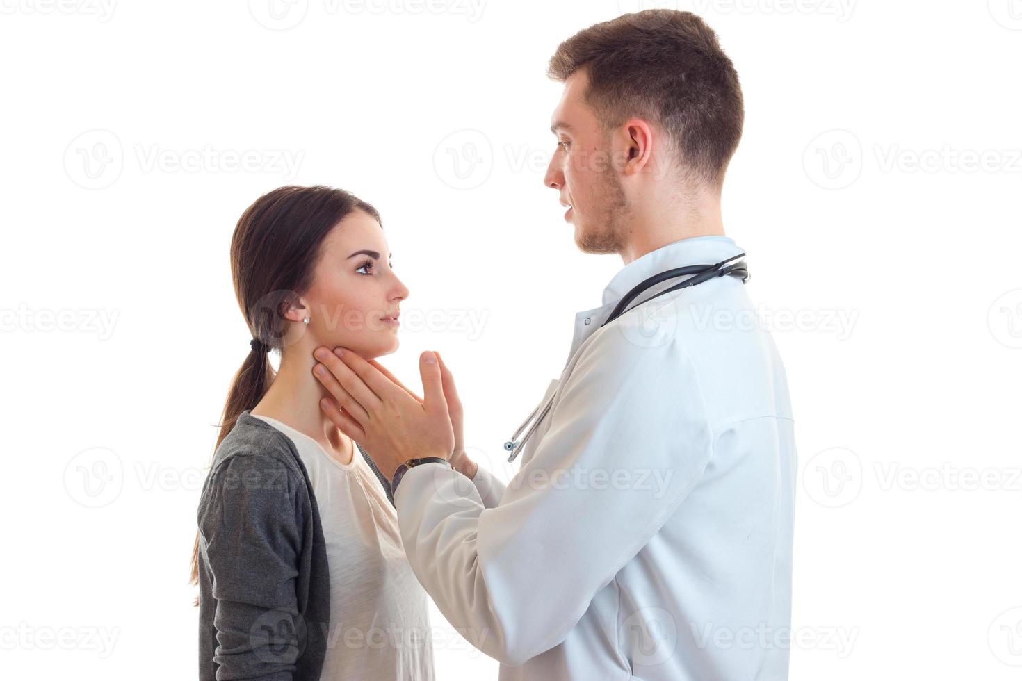 een jong dokter in de jas cheques handen keel schattig meisje foto