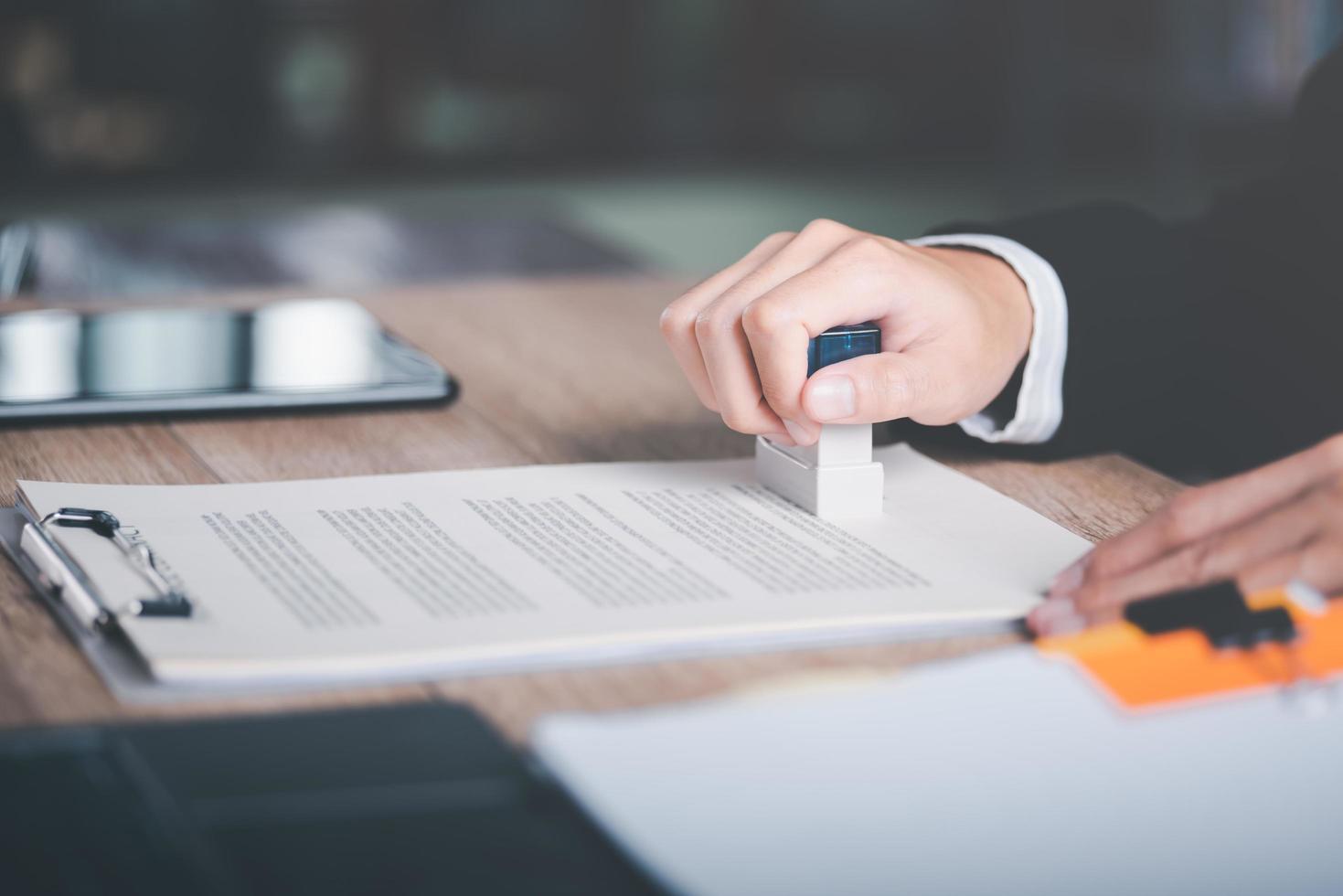 zakenman valideert en beheert bedrijf documenten en overeenkomsten, ondertekening een bedrijf contract goedkeuring van contract documenten bevestiging of garantie certificaat, goedkeuring postzegel foto