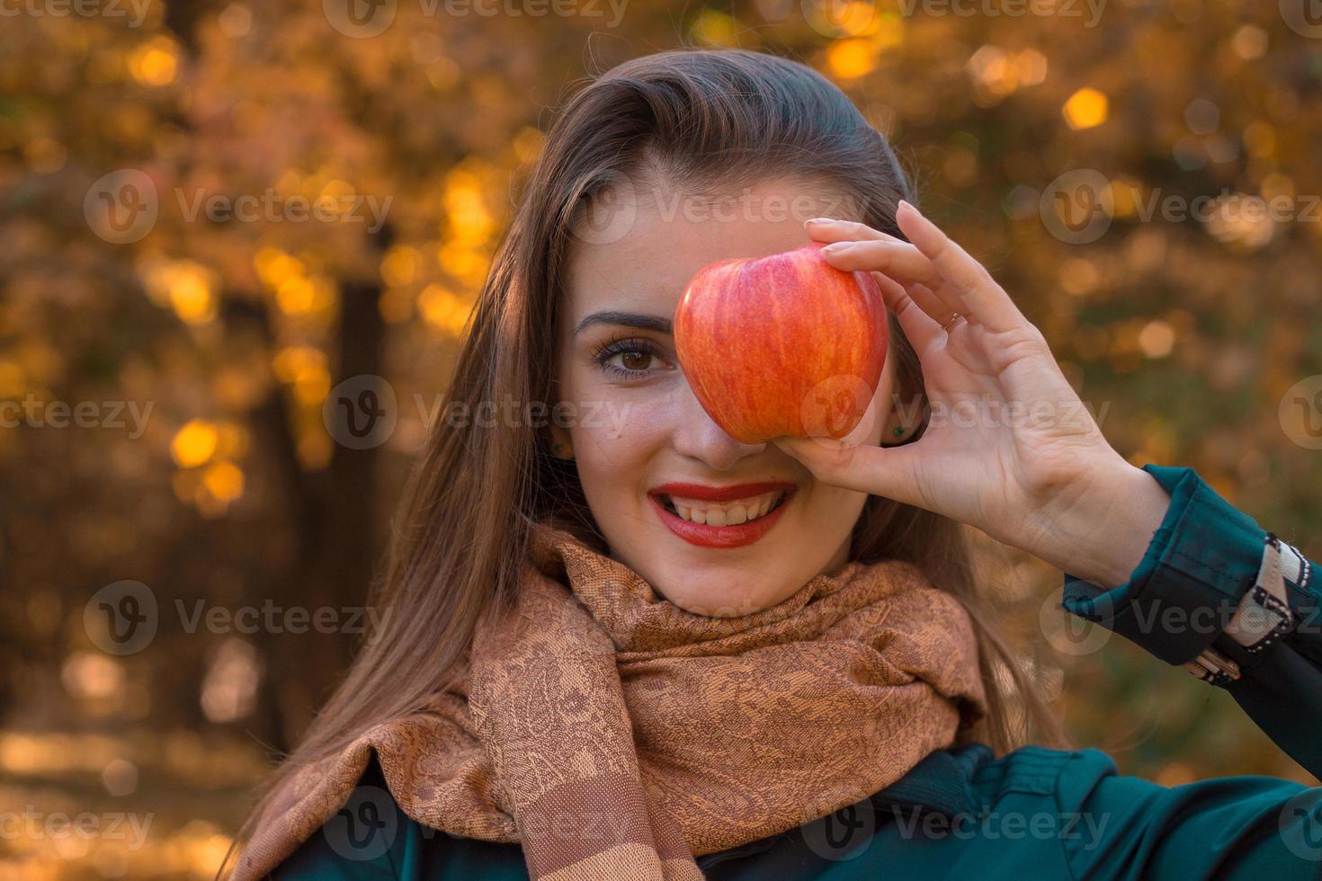 mooi jong meisje houdt appel in de gezicht en glimlacht Bij kroepy plan foto