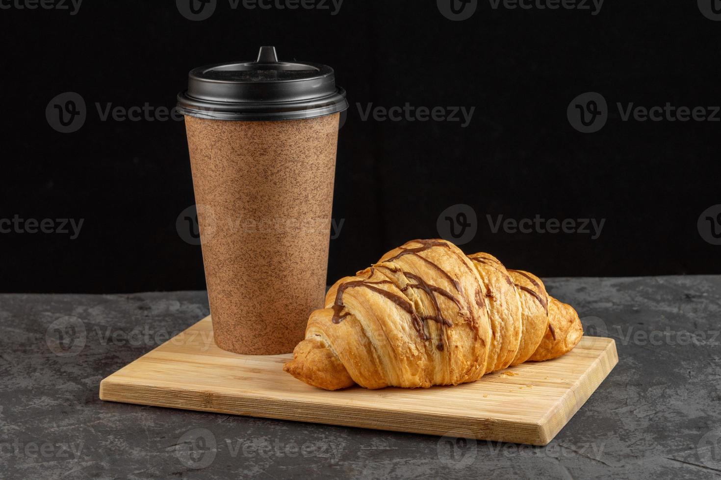 papier kop met geurig koffie en croissant Aan een donker achtergrond. foto