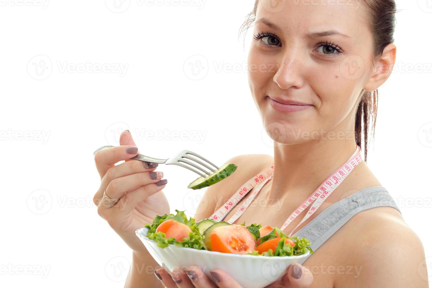 portret van een jong mooi meisje wie glimlacht en eet salade foto