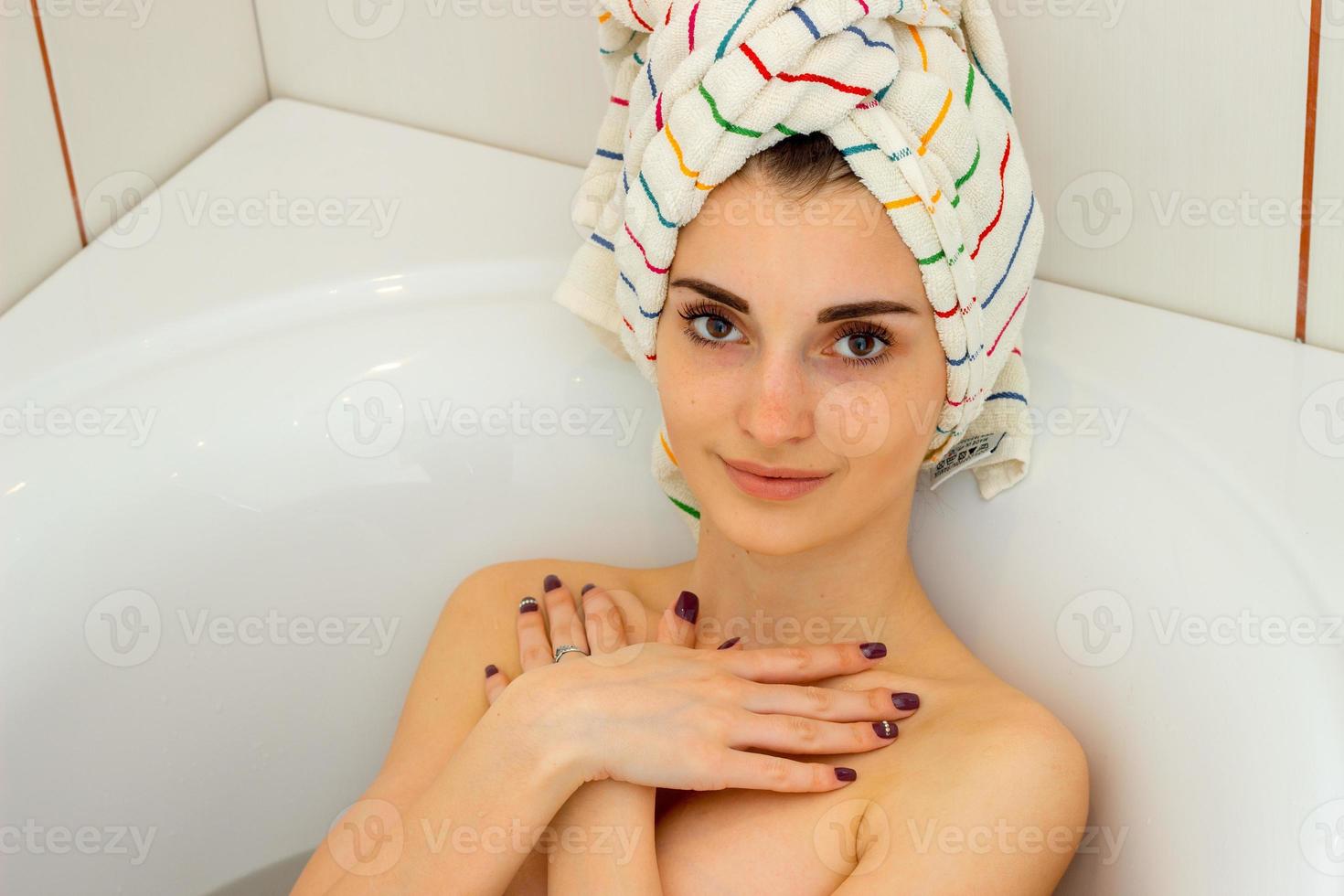 brunette vrouw in de badkamer met een handdoek Aan hoofd foto