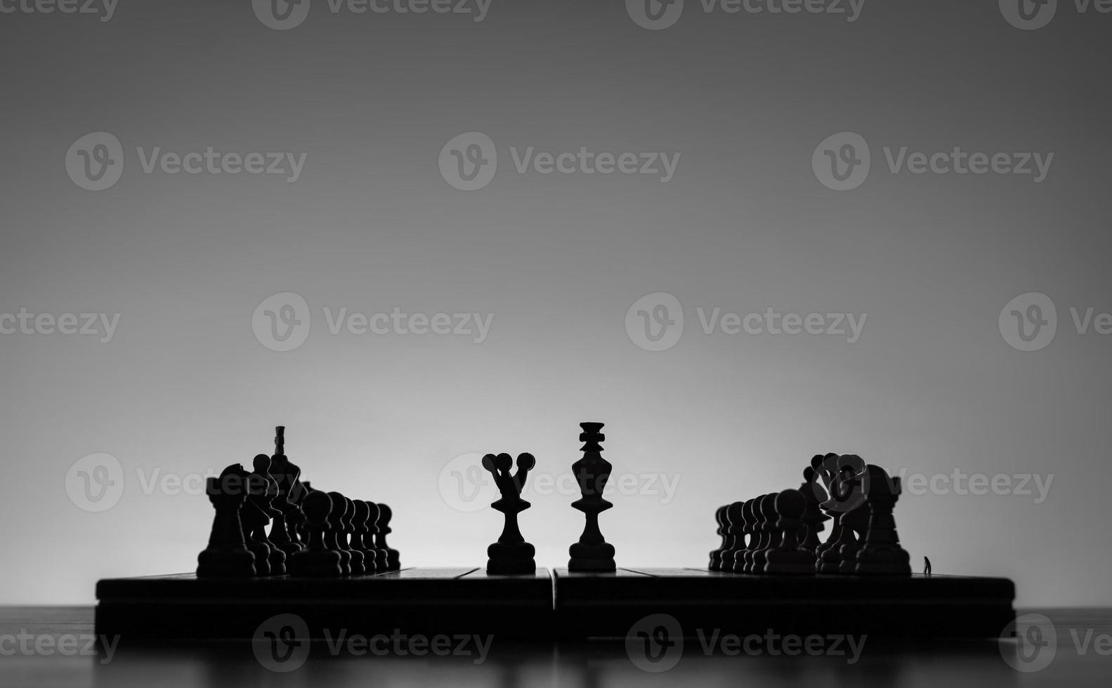 schaak bord met schaak stukken silhouetten Aan wit achtergrond. concept van bedrijf ideeën en wedstrijd en strategie ideeën. zwart en wit klassiek kunst foto. koning en koningin in de midden. foto