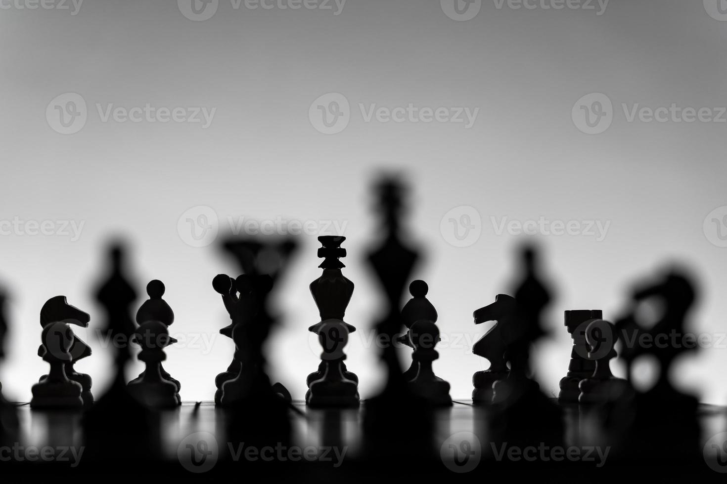schaak bord met schaak stukken silhouetten Aan wit achtergrond. concept van bedrijf ideeën, wedstrijd en strategie ideeën. zwart en wit klassiek kunst foto. allemaal figuur klaar voor strijd, voordat opening foto