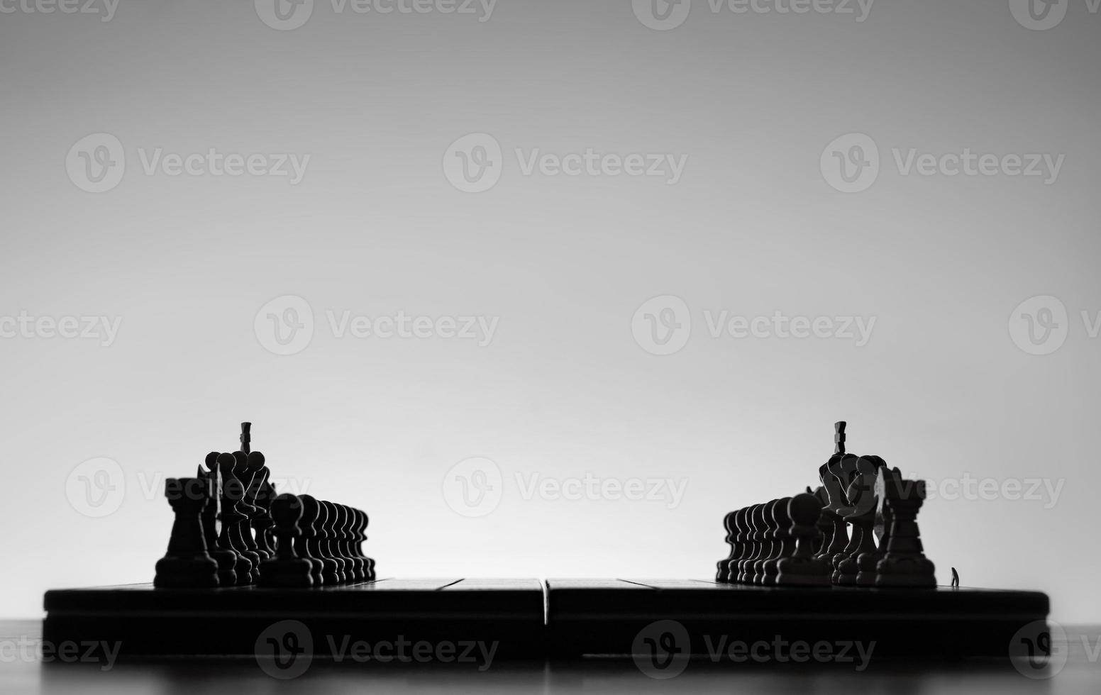 schaak bord met schaak stukken silhouetten Aan wit achtergrond. concept van bedrijf ideeën, wedstrijd en strategie ideeën. zwart en wit klassiek kunst foto. allemaal figuur klaar voor strijd, voordat opening foto